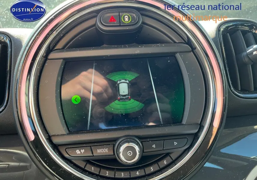 Écran central du MINI Countryman Cooper SE 2019 montrant l'assistance au stationnement, entouré de commandes circulaires.