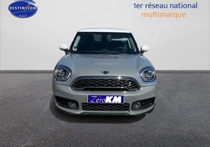 Vue frontale d'une MINI Countryman Cooper SE Moonwalk Grey avec toit et rétroviseurs blancs, calandre chromée.