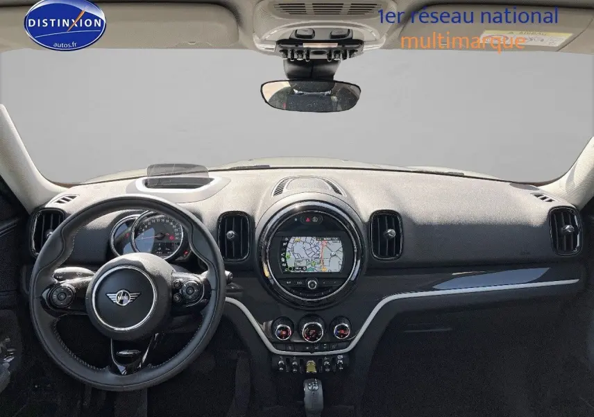 Vue intérieure frontale du tableau de bord noir du MINI Countryman Cooper SE avec écran GPS circulaire et volant multifonction.