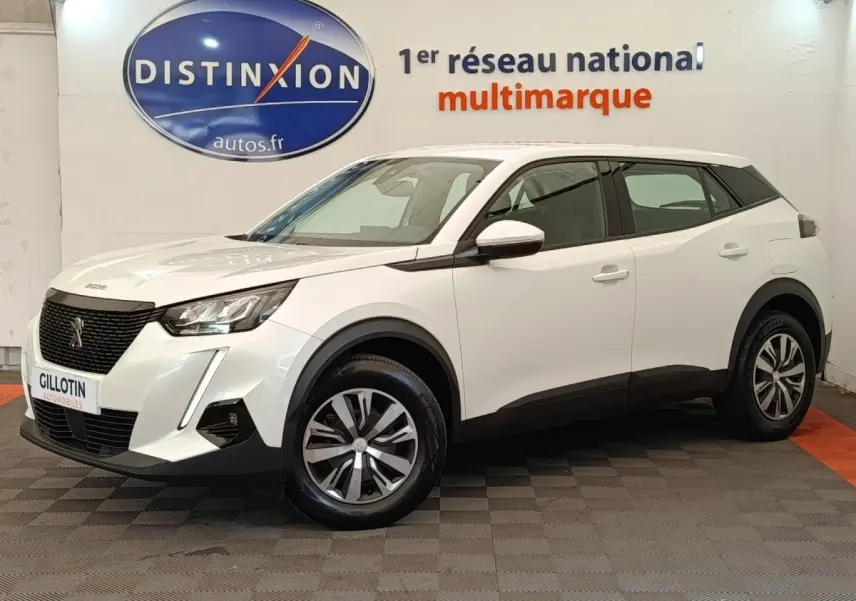 Peugeot 2008 blanc en 3/4 avant droit, avec calandre noire et jantes alliage bicolores, en intérieur showroom.