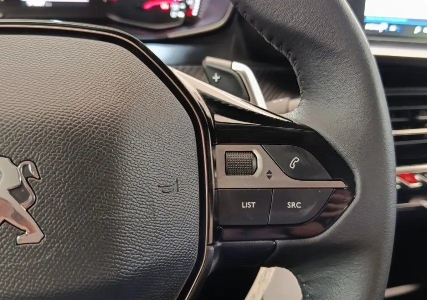 Gros plan sur le volant cuir multifonctions noir du Peugeot 2008, avec commandes audio et téléphone intégrées.