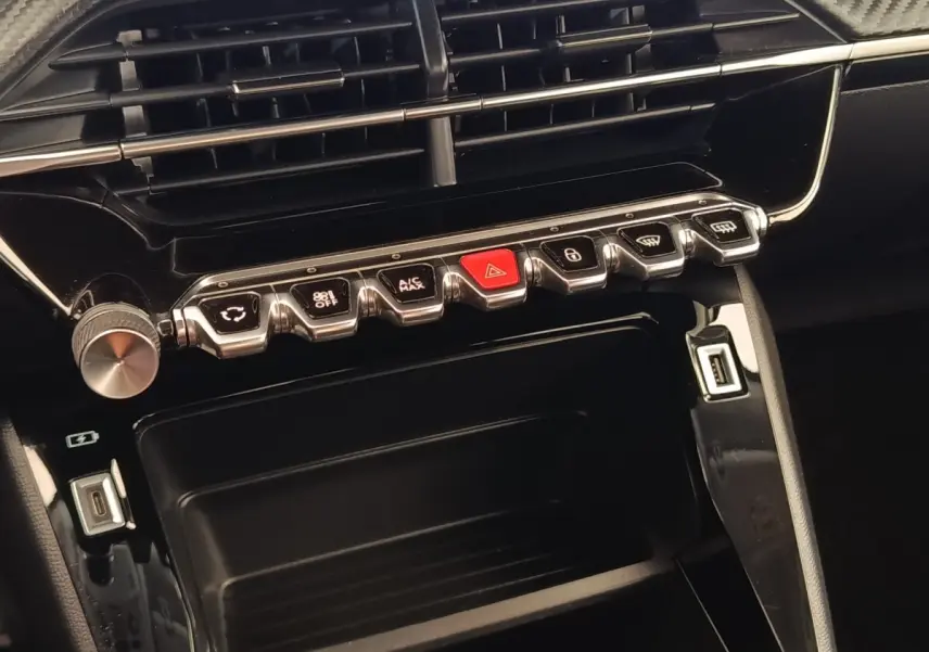 Gros plan sur la console centrale noire du Peugeot 2008 avec boutons de commande et ports USB visibles.