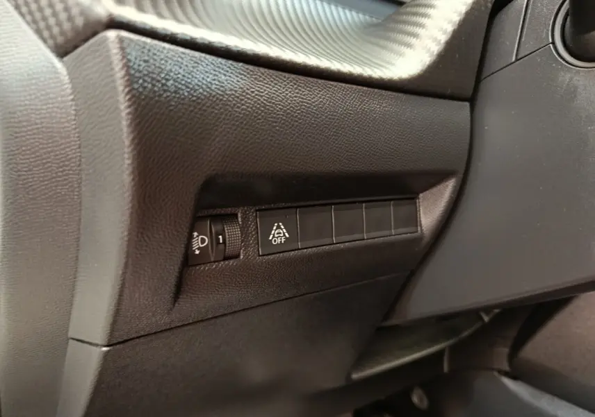 Détail intérieur côté gauche du tableau de bord noir du Peugeot 2008 avec commandes d’éclairage et d’aide à la conduite.