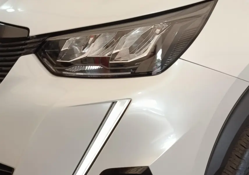 Gros plan sur le phare avant droit blanc du Peugeot 2008 avec signature lumineuse verticale LED.