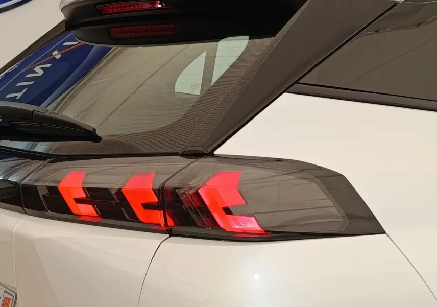 Feu arrière droit allumé d’un Peugeot 2008 blanc, vue rapprochée sur la partie arrière et le toit noir.