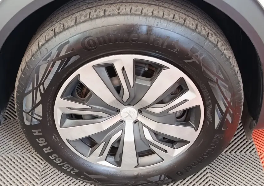 Gros plan sur la roue avant droite d'une Peugeot 2008 blanche, jante alliage au design moderne et pneu Continental.