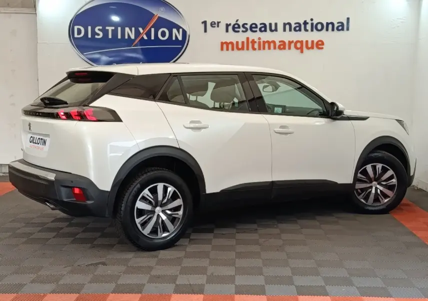 Peugeot 2008 blanc vue de profil côté droit en intérieur avec jantes alliage et toit noir contrasté.