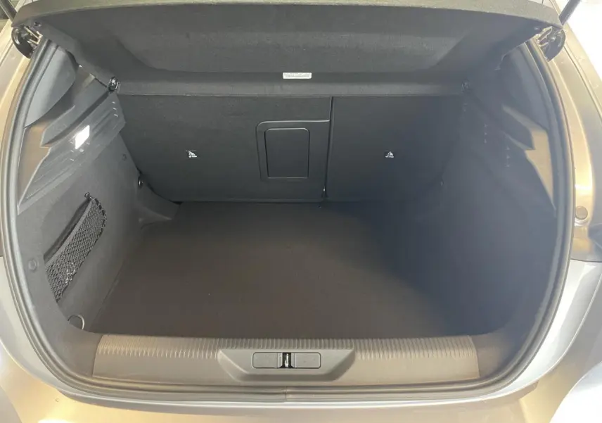 Coffre ouvert vu de l'arrière d'une Peugeot 308 gris Artense avec intérieur noir et filet de rangement latéral.