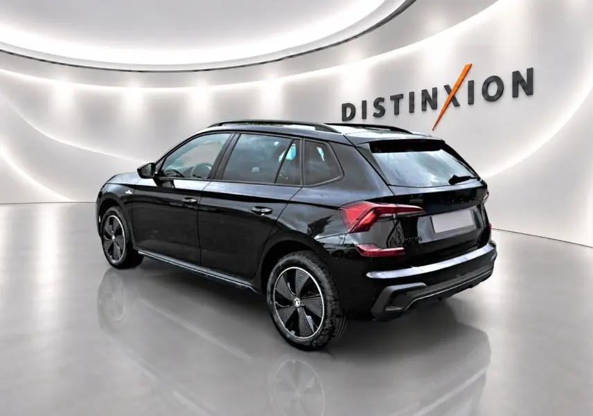 Vue 3/4 arrière droite d'un Skoda Kamiq noir avec jantes alu et toit panoramique en showroom lumineux.