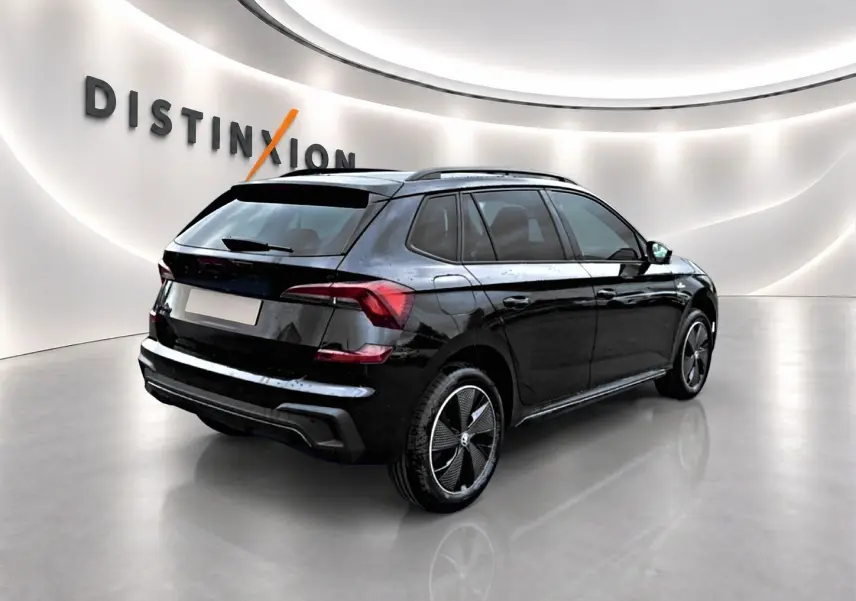 Vue 3/4 arrière droite d'un Skoda Kamiq noir avec jantes alu noires et toit panoramique en showroom lumineux.