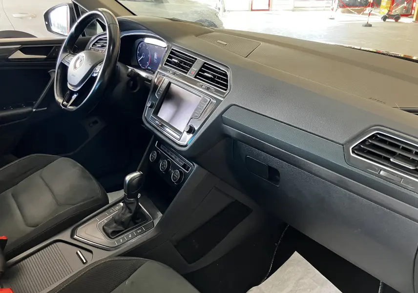 Intérieur noir du Volkswagen Tiguan 2017, vue côté conducteur sur tableau de bord et console centrale avec boîte auto.