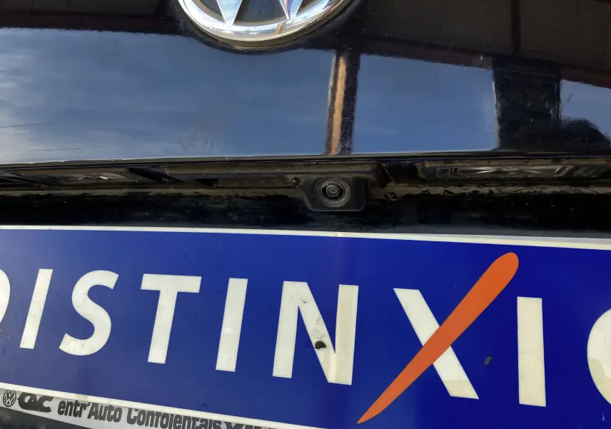 Gros plan sur la caméra de recul noire sous le logo Volkswagen sur la malle arrière d’un Tiguan noir.