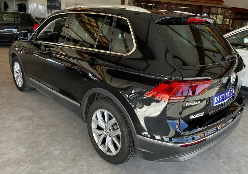 Vue 3/4 arrière droite d'un Volkswagen Tiguan noir 2017 avec jantes alliage et feux arrière LED en intérieur showroom.