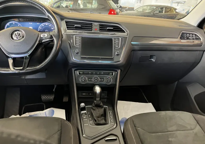 Vue intérieure du tableau de bord et console centrale du Volkswagen Tiguan noir 2017 avec volant multifonction et écran tactile éteint.