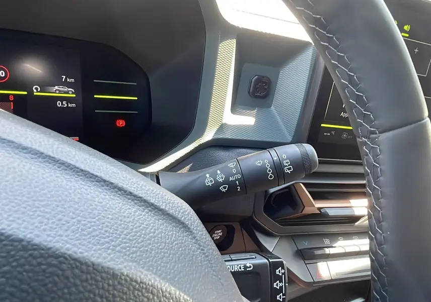 Gros plan sur le volant et le tableau de bord numérique du Dacia Duster blanc 2025, version New TCe 130 4x4 Extreme Plus.