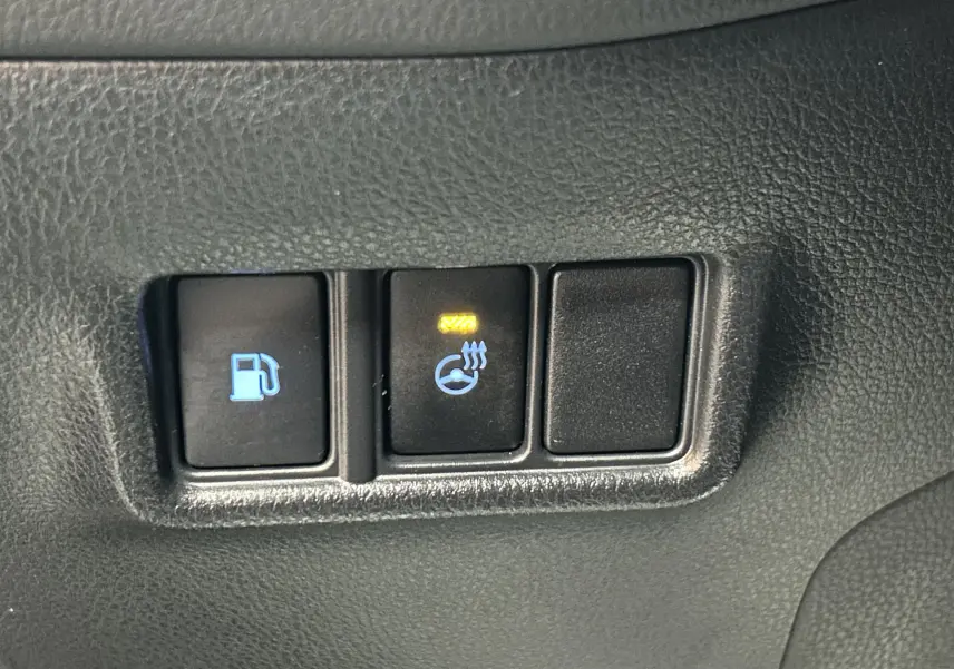 Gros plan sur les boutons de commande intérieurs avec témoin allumé du volant chauffant du Toyota C-HR Hybride noir métal.