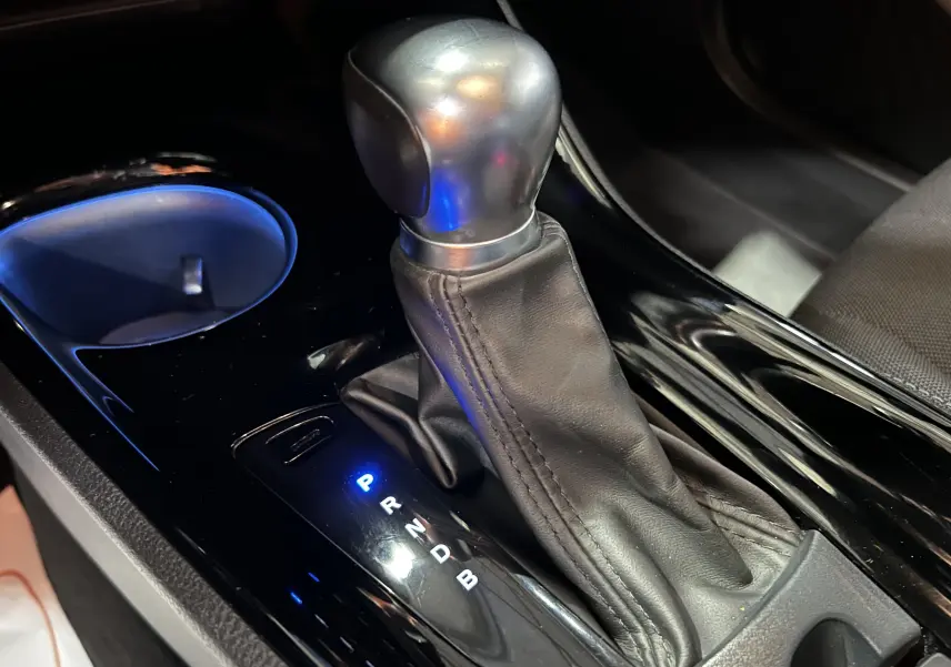 Le levier de vitesses automatique en cuir noir du Toyota C-HR Hybride 122h Edition 2WD vu en gros plan intérieur.