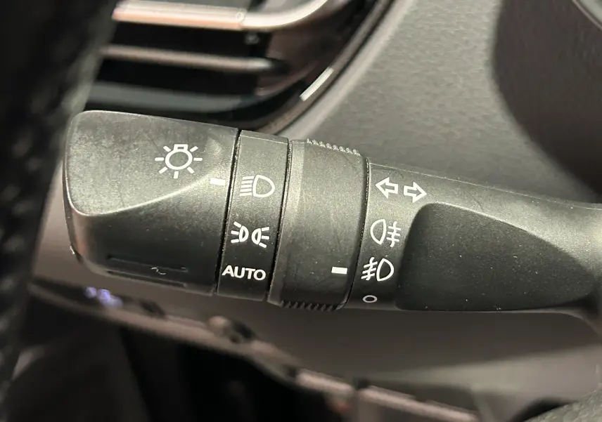 Gros plan sur la commande des phares et clignotants du Toyota C-HR Hybride 122h Edition 2WD noir métal, intérieur.