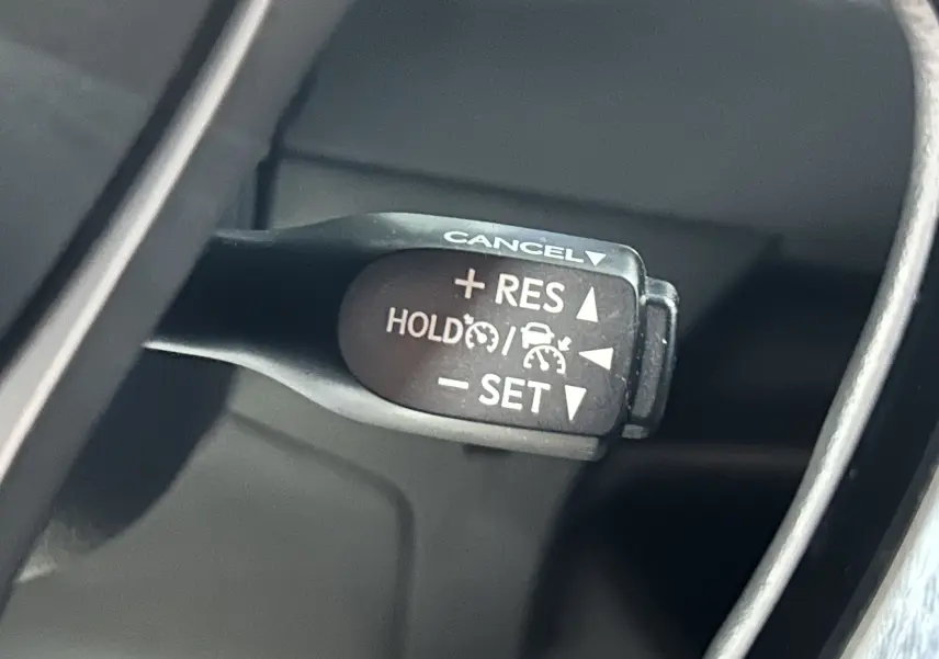 Gros plan sur le levier de régulateur de vitesse du Toyota C-HR Hybride noir métal, version 2021, intérieur côté gauche.