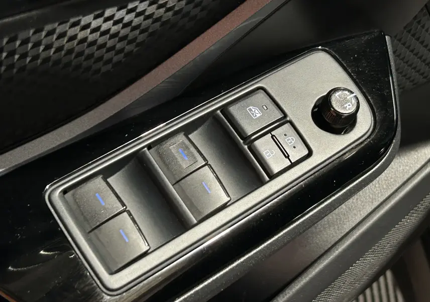 Gros plan sur les commandes de lève-vitres et réglage des rétroviseurs côté conducteur du Toyota C-HR Hybride noir métal 2021.