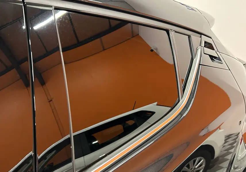 Reflet du profil arrière droit du Toyota C-HR Hybride noir métal 2021, soulignant ses lignes anguleuses et sa vitre teintée.