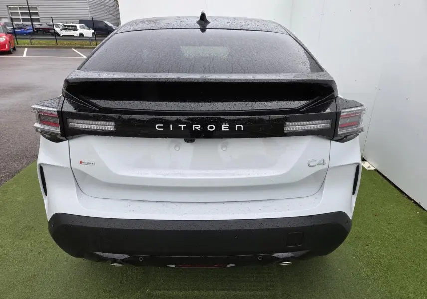Vue arrière d'une Citroën C4 blanche avec toit noir et feux arrière LED distinctifs sous la pluie.