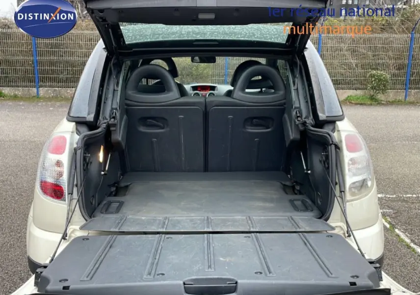 Vue arrière ouverte d'une Citroën C3 Pluriel ivoire de 2007, montrant le coffre et les dossiers de sièges rabattus.