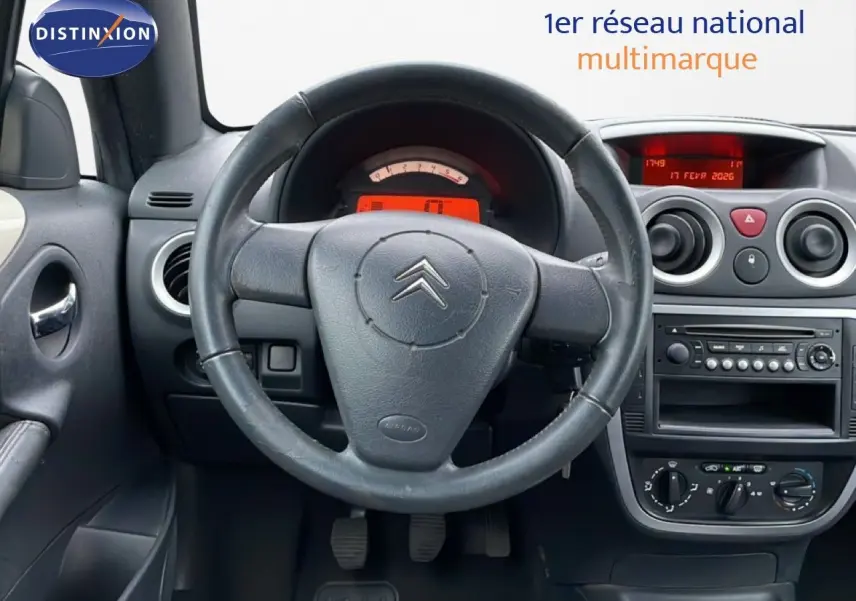 Intérieur de Citroën C3 Pluriel ivoire 2007, vue frontale du tableau de bord avec volant cuir et console centrale.