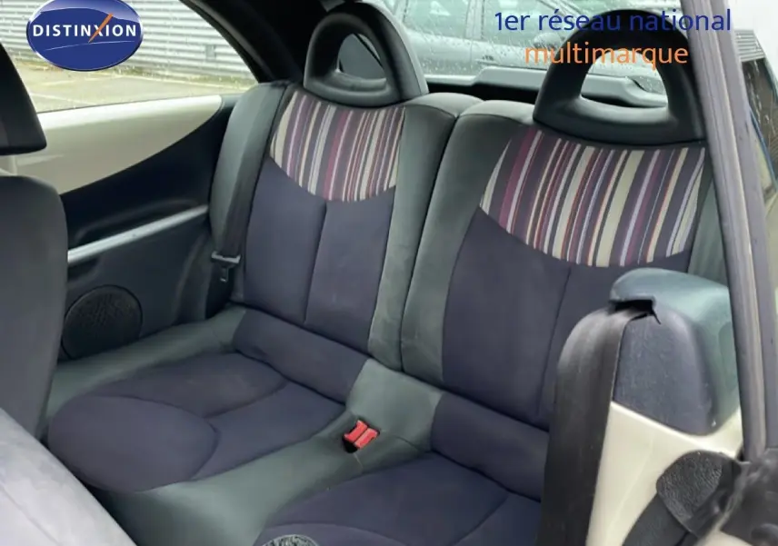 Vue intérieure arrière montrant les sièges arrière en tissu noir et beige avec motifs rayés sur une Citroën C3 Pluriel ivoire.