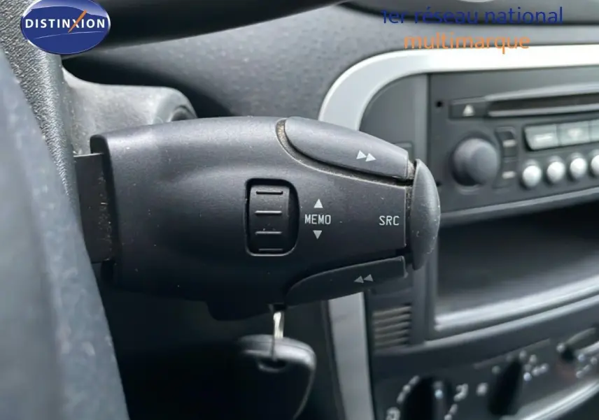 Gros plan sur la commande au volant côté gauche d’une Citroën C3 Pluriel ivoire, tableau de bord en arrière-plan.
