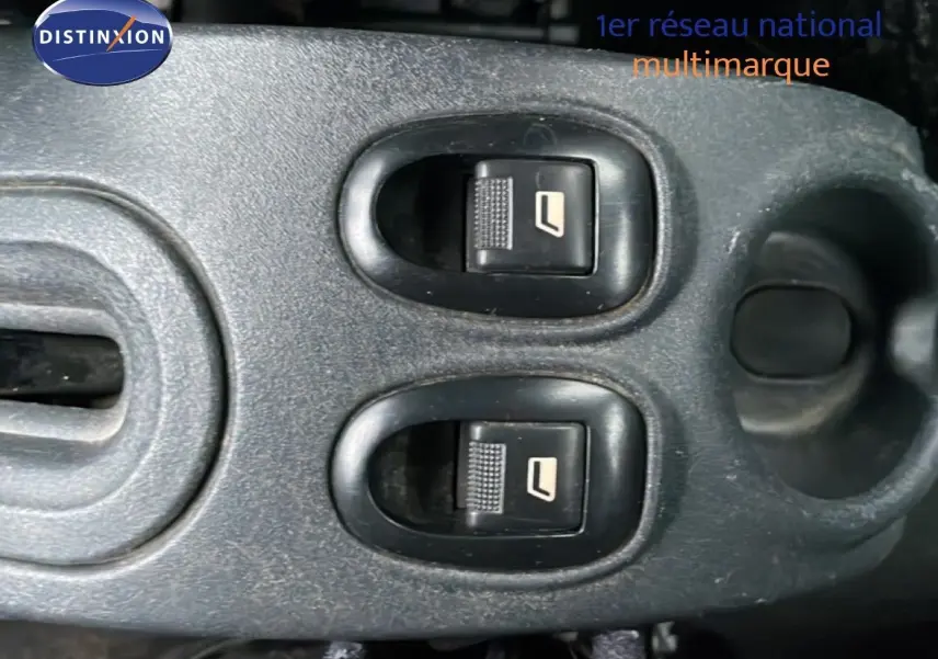 Gros plan sur les commandes électriques des vitres avant dans l’habitacle d’une Citroën C3 Pluriel ivoire de 2007.
