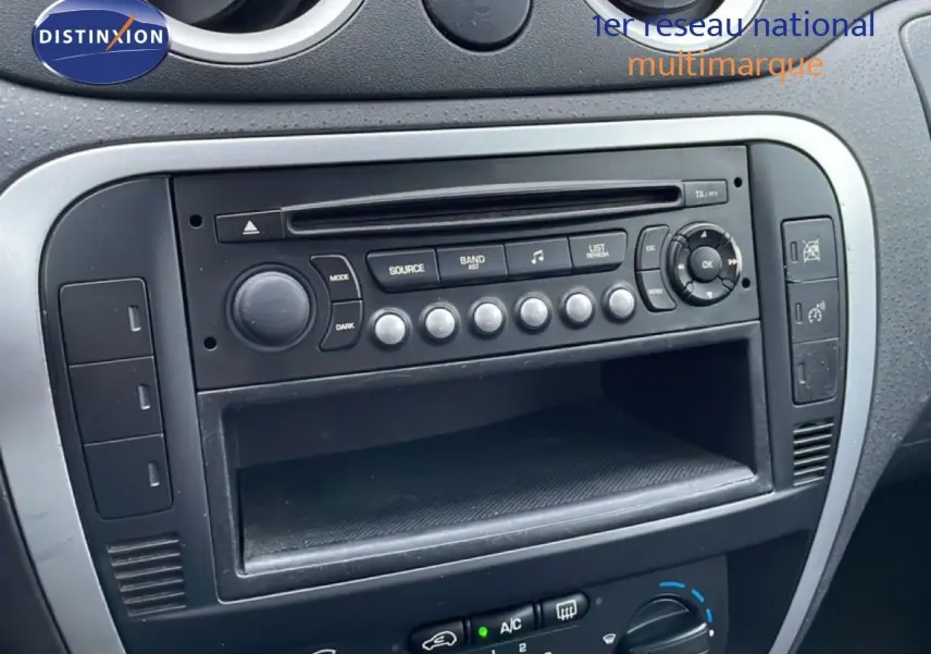 Vue rapprochée de la console centrale noire d’une Citroën C3 Pluriel 1.4 HDI 70CH avec autoradio et commandes de climatisation.
