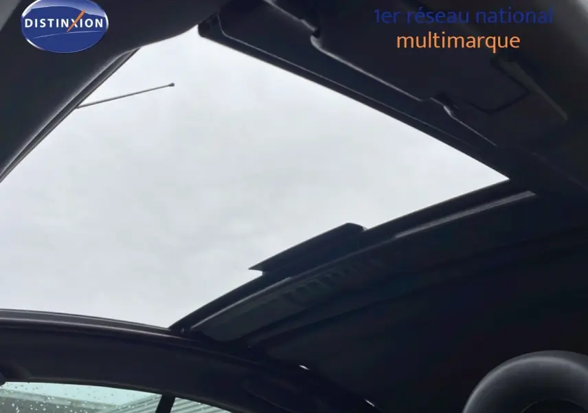 Toit ouvrant panoramique ouvert sur une Citroën C3 Pluriel ivoire, vue intérieure vers le ciel gris.