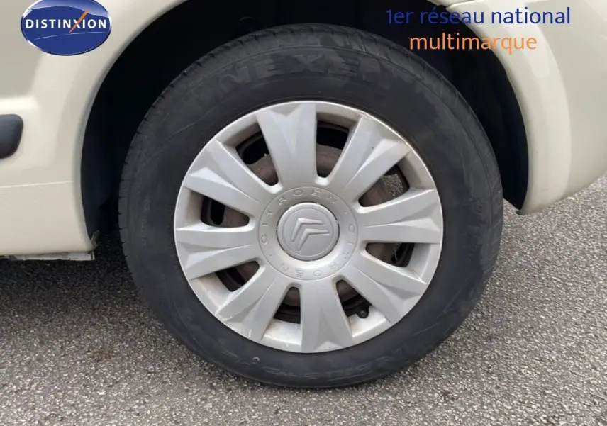 Gros plan sur la roue avant gauche ivoire d'une Citroën C3 Pluriel 1.4 HDI 70ch avec enjoliveur d'origine.