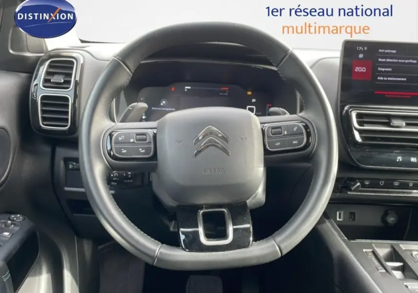 Vue intérieure centrée sur le volant cuir multifonctions et le cockpit numérique du Citroën C5 Aircross 2024.