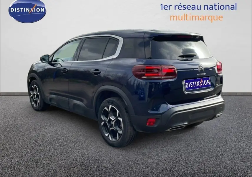 Vue 3/4 arrière droite d'un Citroën C5 Aircross bleu 2024 avec jantes aluminium et feux arrière allumés.