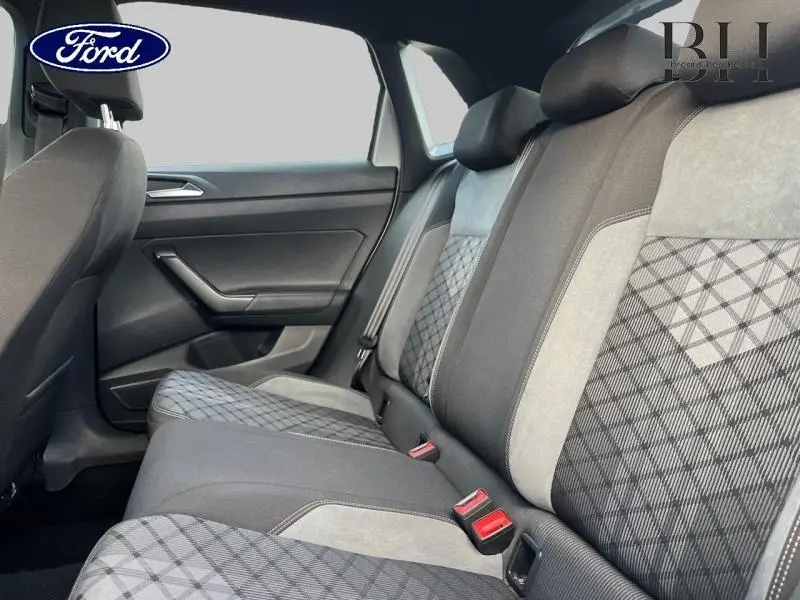 Vue intérieure de la banquette arrière de la Volkswagen Polo 2022 avec sellerie tissu noir et motifs gris à losanges.