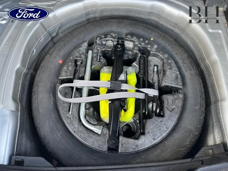 Gros plan sur la roue de secours à encombrement réduit et ses outils dans le coffre d'une Volkswagen Polo Reflet d'Argent.