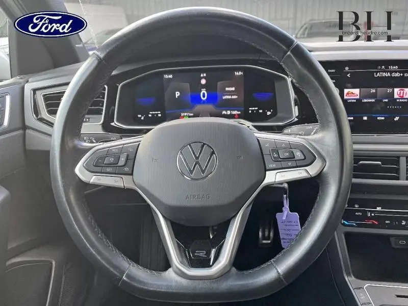 Vue rapprochée du volant cuir multifonction Volkswagen Polo 2022 avec tableau de bord numérique et écran tactile.