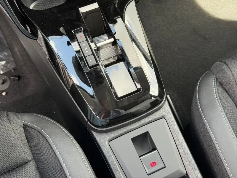 Gros plan sur la console centrale noire brillante avec levier de boîte auto et frein à main électrique dans Citroën C3 Aircross Vert Montana.