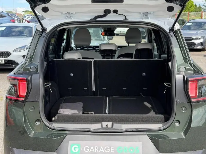 Coffre ouvert vu de l'arrière d'un Citroën C3 Aircross Vert Montana avec intérieur clair et sièges arrière partiellement rabattus.