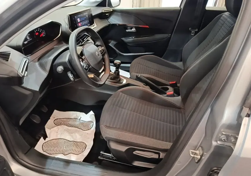 Vue intérieure côté conducteur de la Peugeot 208 gris clair, volant cuir multifonctions et tableau de bord digital.