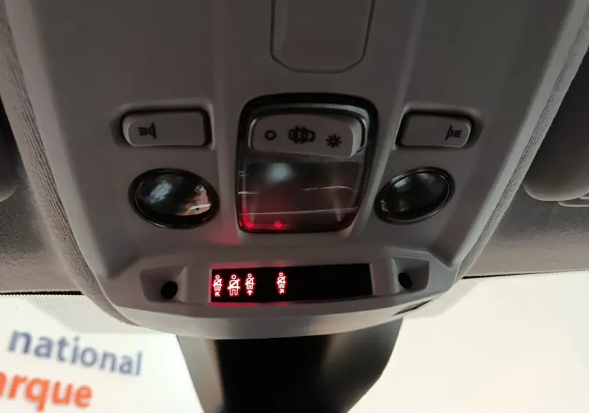 Vue en gros plan du plafonnier gris clair de la Peugeot 208 PureTech 100 avec voyants de ceinture allumés.