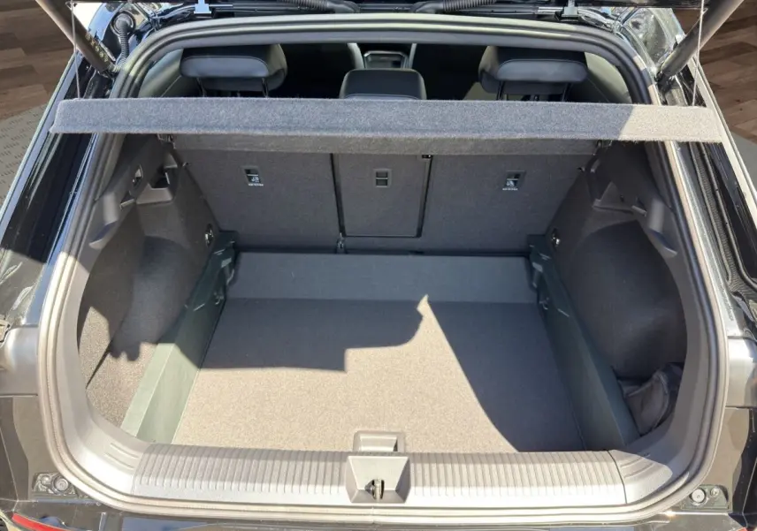 Coffre ouvert vu de l'arrière d'un Volkswagen T-Roc noir, montrant l'espace de chargement et la tablette cache-bagages.