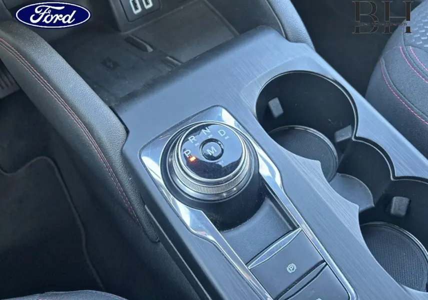 Vue rapprochée de la console centrale du Ford Kuga 2021 avec molette de boîte auto, finition noire et coutures rouges.