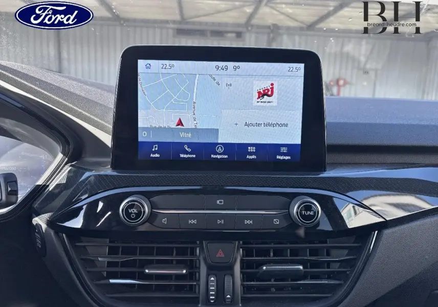 Vue rapprochée de la console centrale du Ford Kuga 2021 avec écran tactile affichant la navigation et commandes audio.