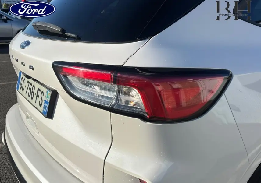 Vue 3/4 arrière droite d'un Ford Kuga blanc Premium Platinum avec feux arrière LED et hayon mains libres.