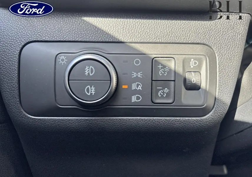 Gros plan sur les commandes d’éclairage du tableau de bord du Ford Kuga 1.5 EcoBlue blanc, avec bouton rotatif et réglages LED.