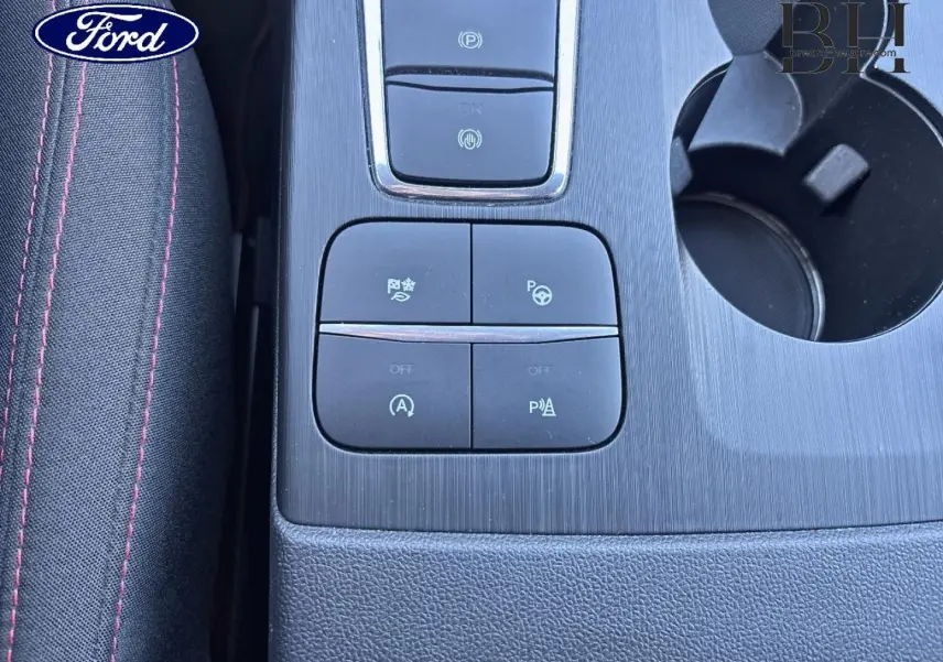 Gros plan sur la console centrale noire du Ford Kuga 2021, avec boutons de contrôle et porte-gobelets visible.