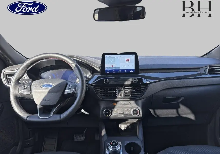Vue frontale de l'intérieur du Ford Kuga 1.5 EcoBlue 2021, tableau de bord noir avec écran tactile et volant cuir multifonction.